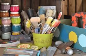 Photographie d'une table avec pots de peinture et pinceaux